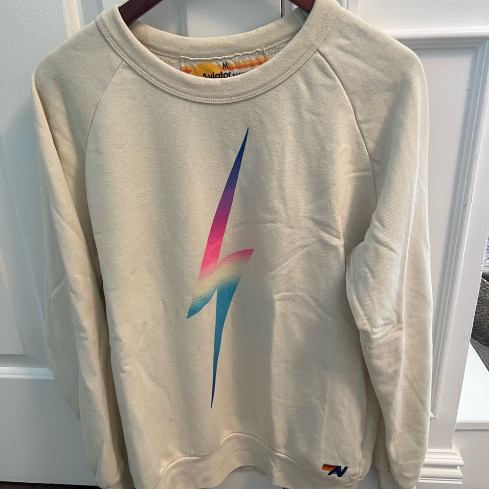Aviator Nation sweatshirt in Sand color on medium, with pastel bolt on front.